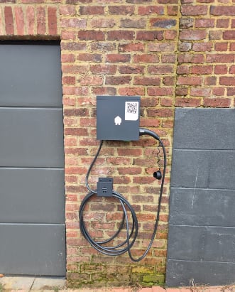 Borne de recharge Smappee installée sur une façade en briques pour un domicile ou un parking d'entreprise dans le Brabant Wallon.